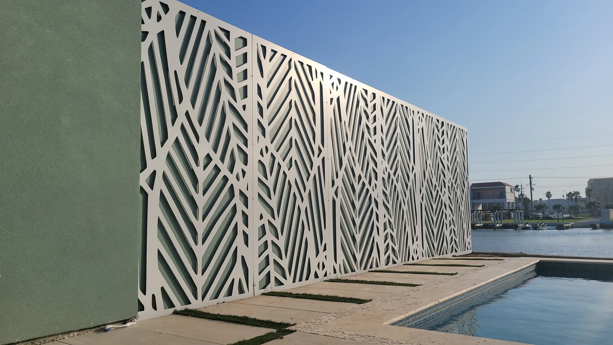 White decorative privacy fence panels along a waterfront pool